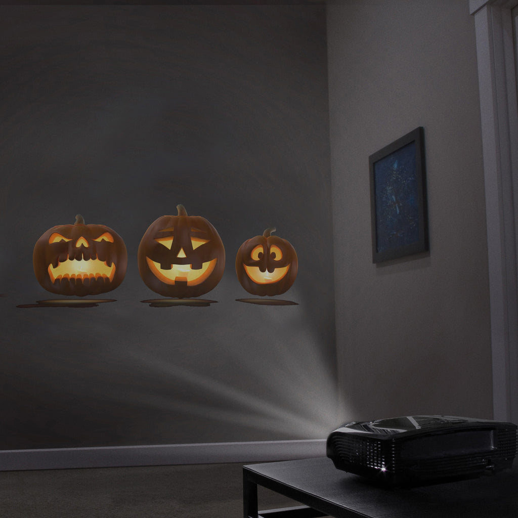 Jack-o-lantern pumpkin projections on a wall with a projector on table