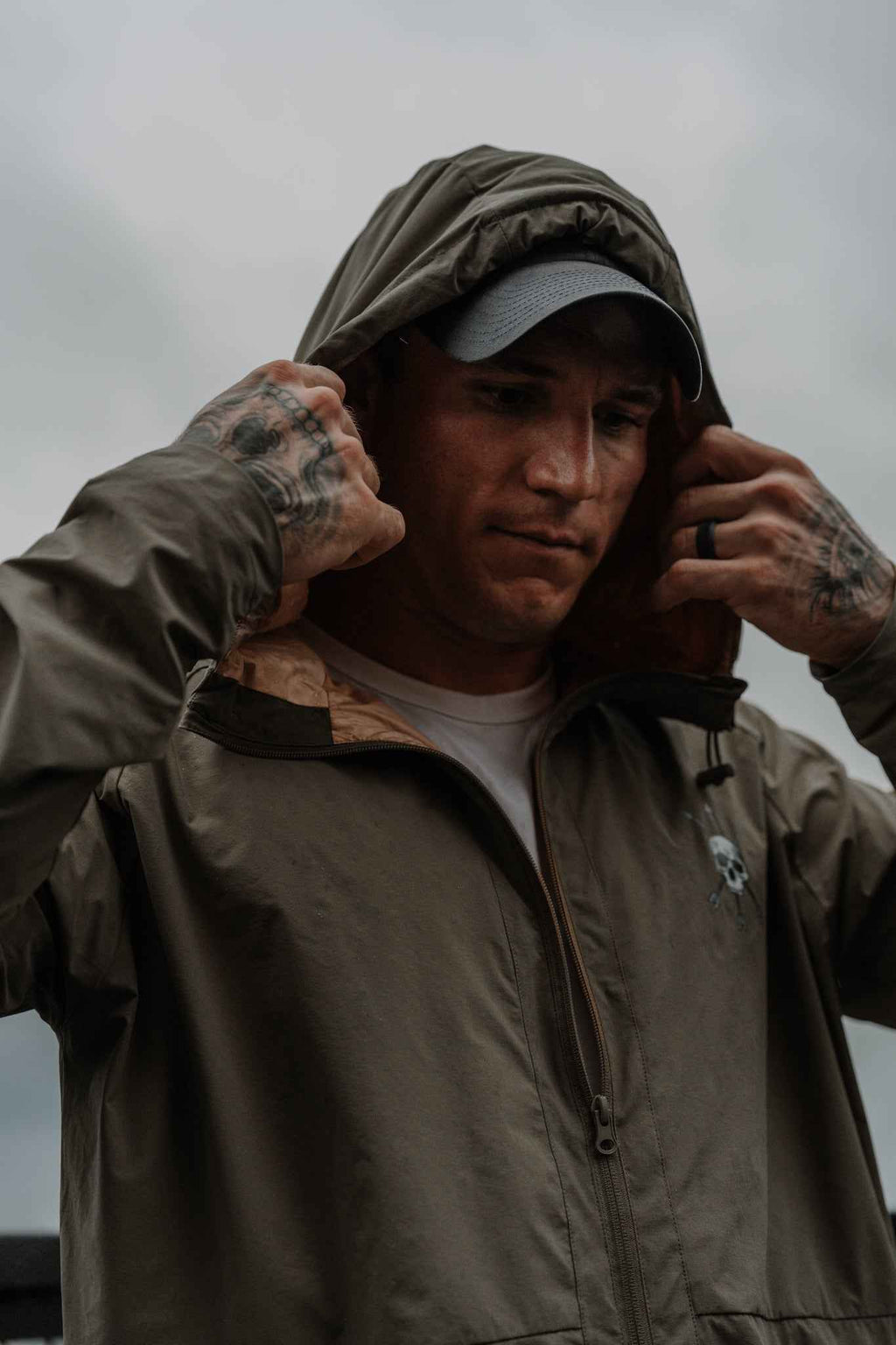 Men's olive hooded jacket on model, full-zip front and skull chest logo