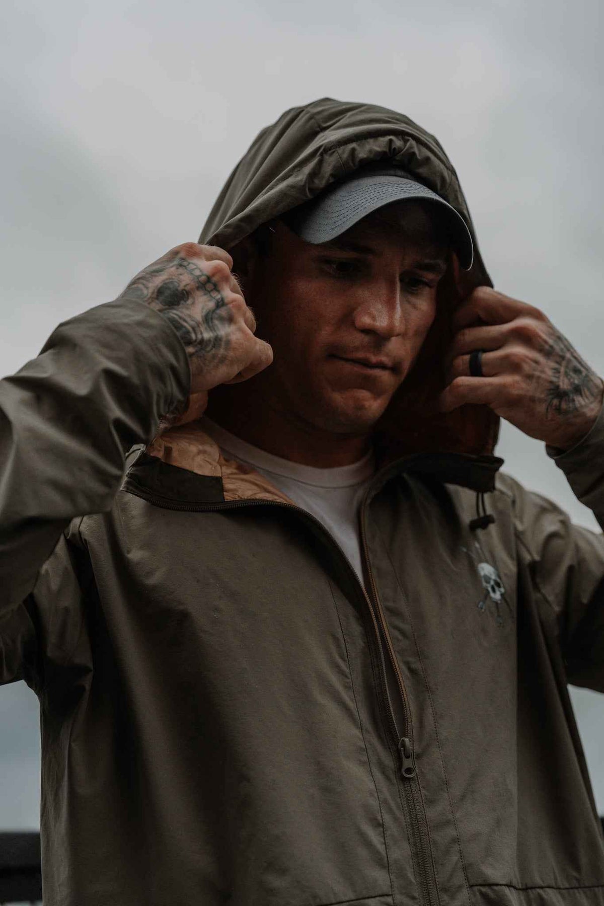 Men's olive hooded jacket on model, full-zip front and skull chest logo