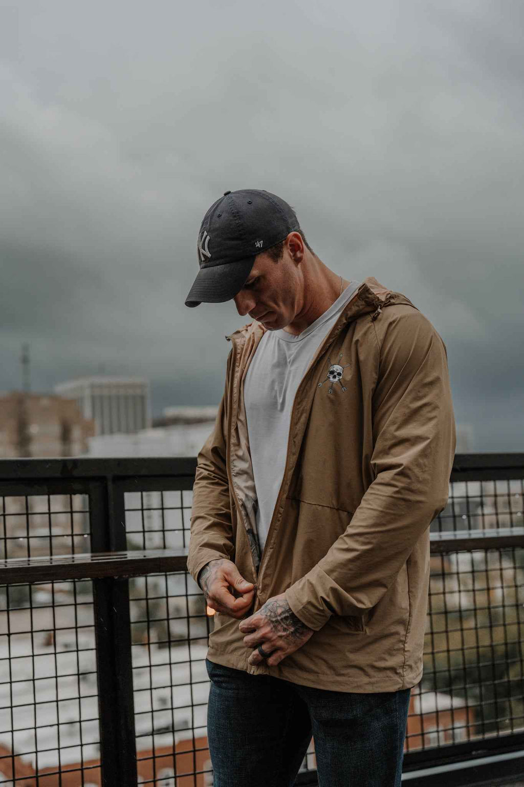 Men's olive Journey jacket with hood and zip front, worn with dark jeans