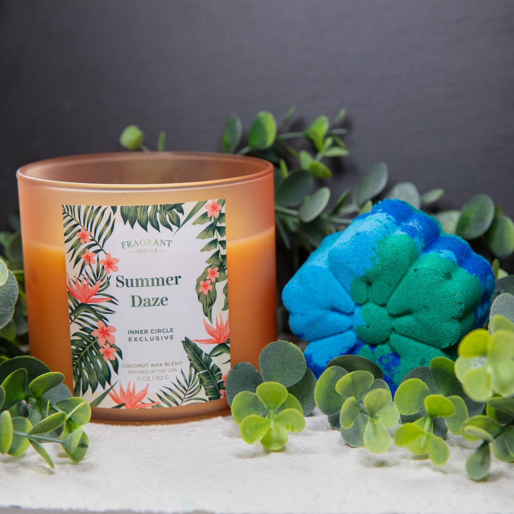 Orange glass candle with floral label, beside blue flower-shaped bath bomb
