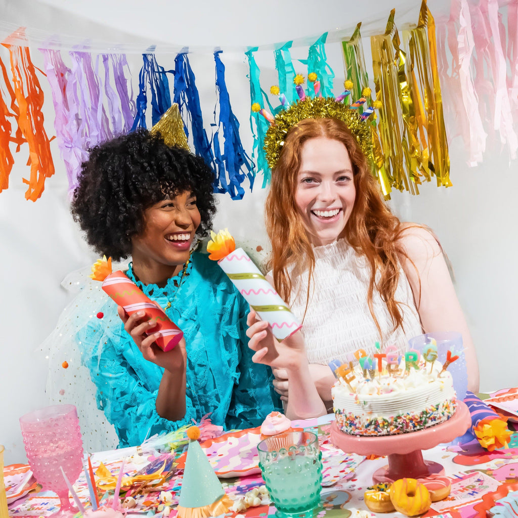 Birthday crackers held by two guests, striped tubes with orange flame ends