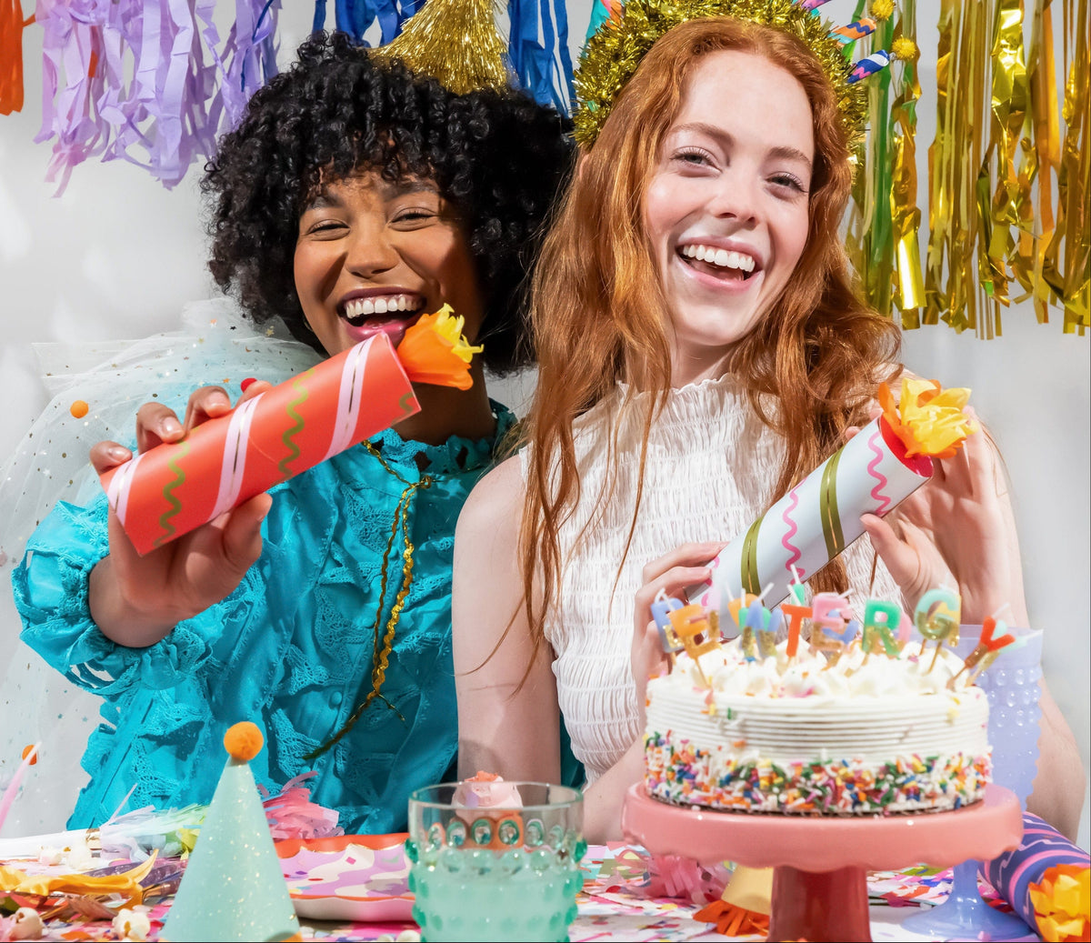 Two party guests holding birthday crackers, striped tubes with orange paper flame tips