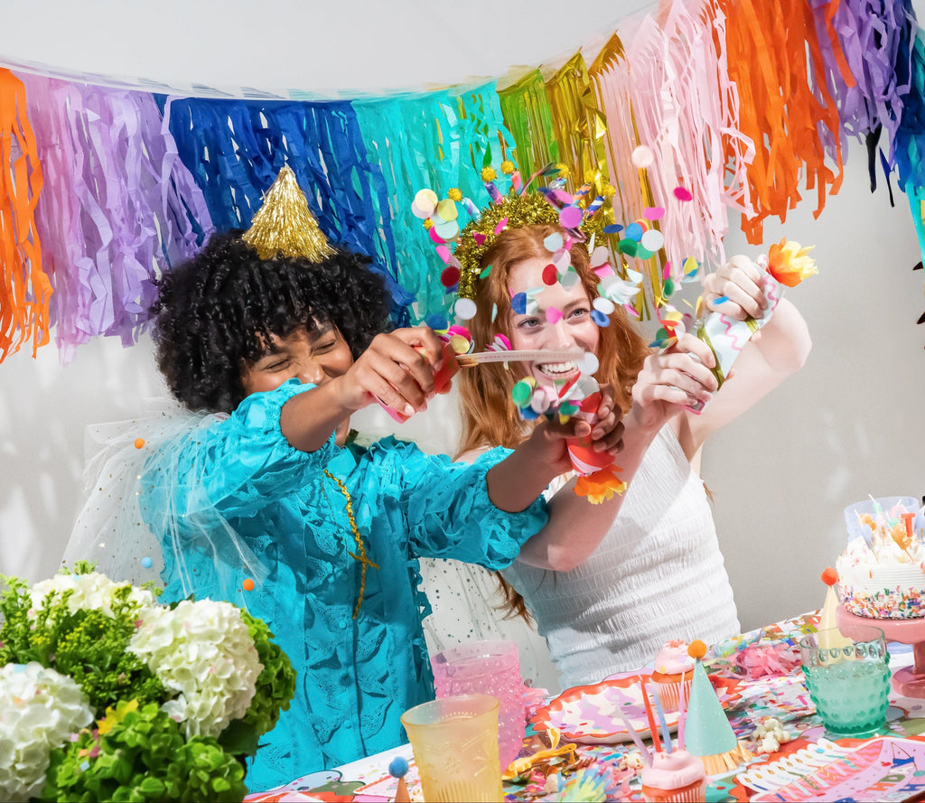 Birthday crackers in guests' hands, striped tubes with orange and confetti pop