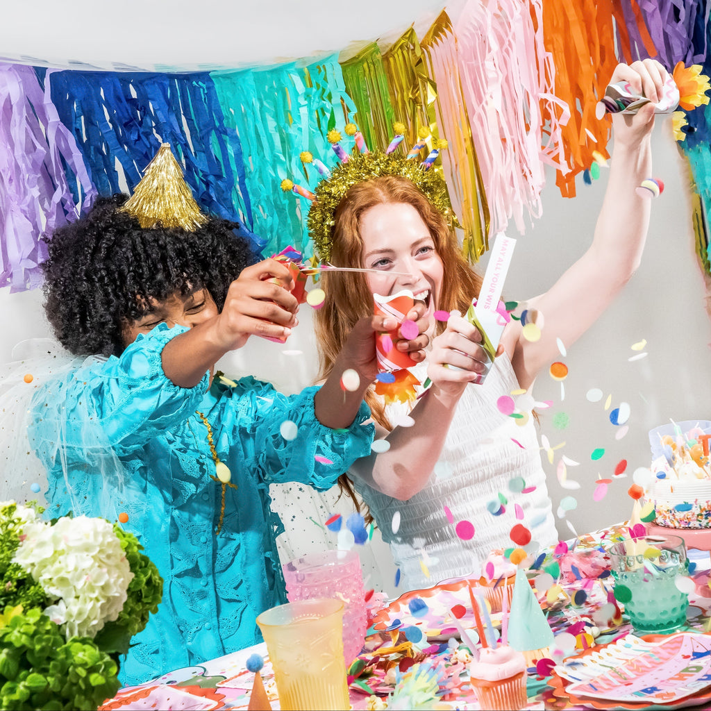 Birthday party cracker set with confetti, candle-style crackers held up by two people