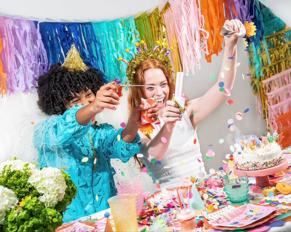 Birthday party cracker set with confetti, candle crackers in hands near a birthday cake