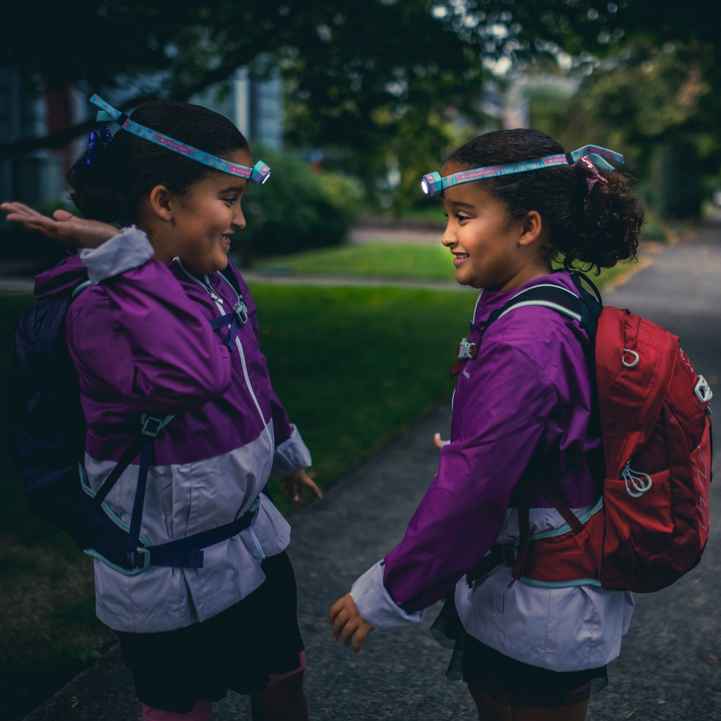 Kids wearing headlamps while walking outdoors, front lights shining on headbands