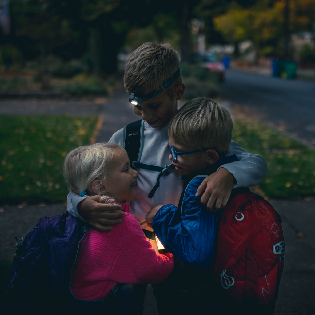 Kids wearing headlamps outdoors, white LEDs shining on the front of each headband