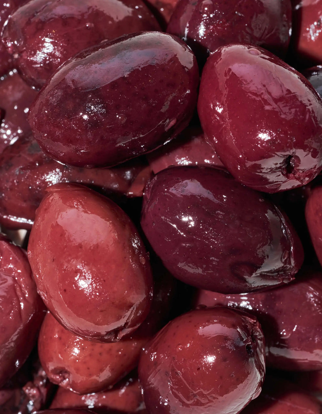 Kalamata olives, dark purple-red pitted pieces with a glossy surface