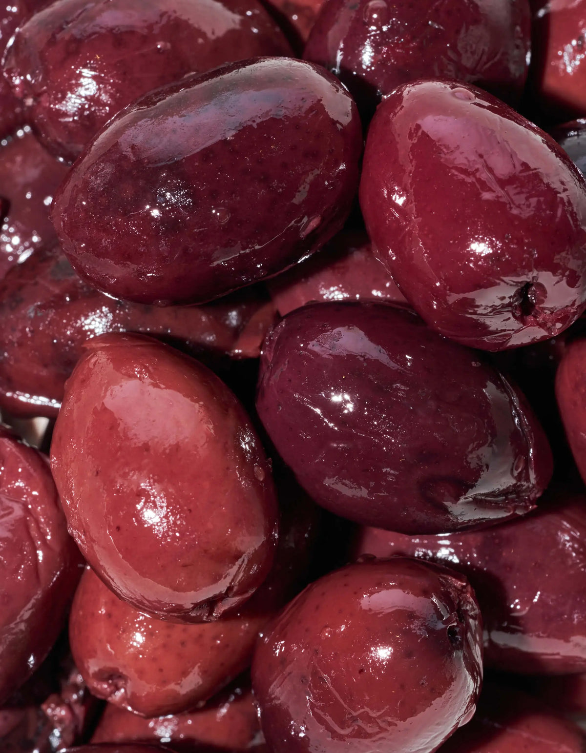 Kalamata olives, dark purple-red pitted pieces with a glossy surface