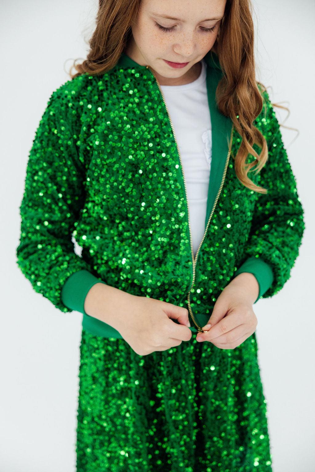 Green velvet sequin jacket with zip front and stand collar, hands on zipper