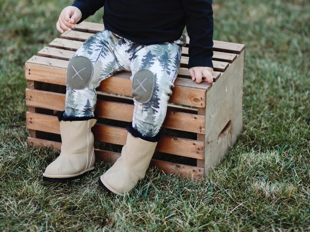 Kids’ beige slip-on boots with dark soles on wooden crate