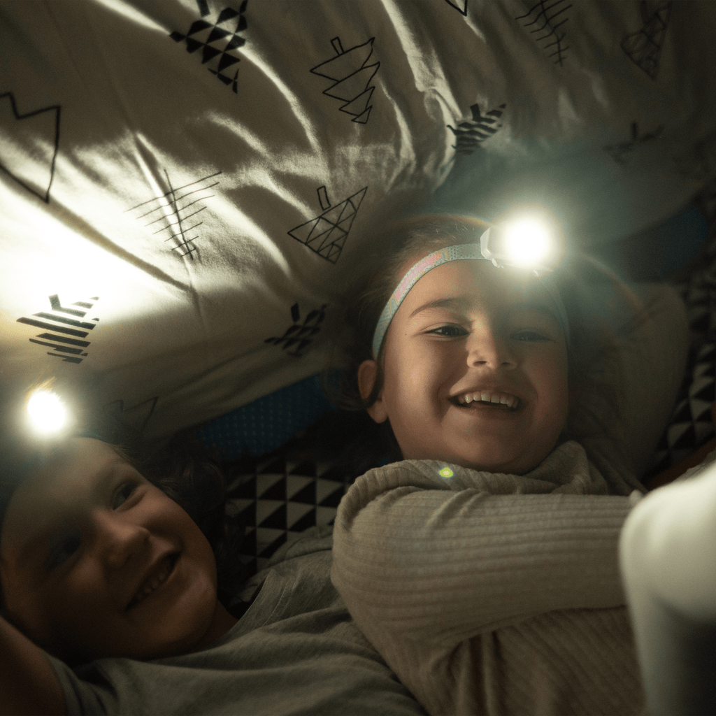 Kids headlamp glowing on child’s forehead under tent