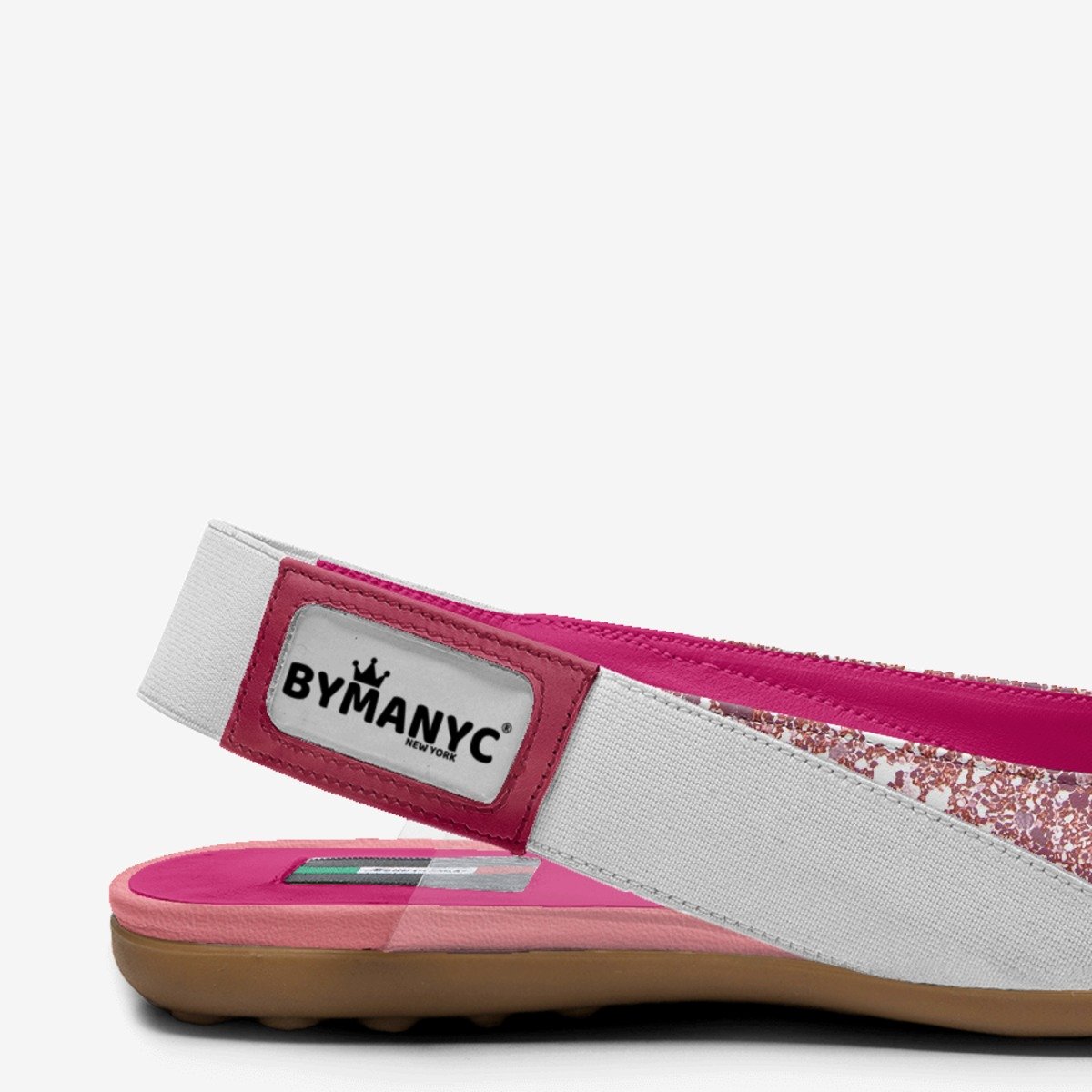 Kids' ballerina flats close-up: BYMANYC label, white elastic band, pink glitter upper