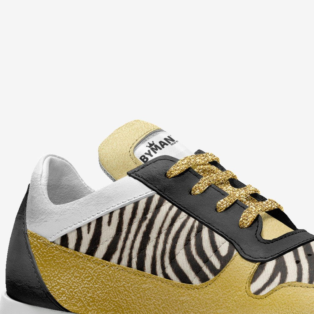 Kids' zebra-print vegan sneakers with BYMAN label, gold glitter laces, black side panels.
