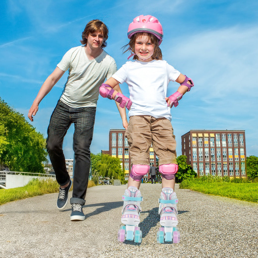 Kids pink quad roller skates with light-up wheels, side view on child's feet