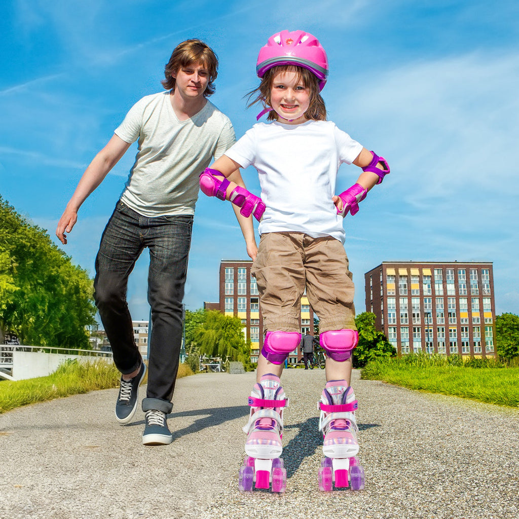 Kids pink quad roller skates with light-up wheels, worn on a child's feet
