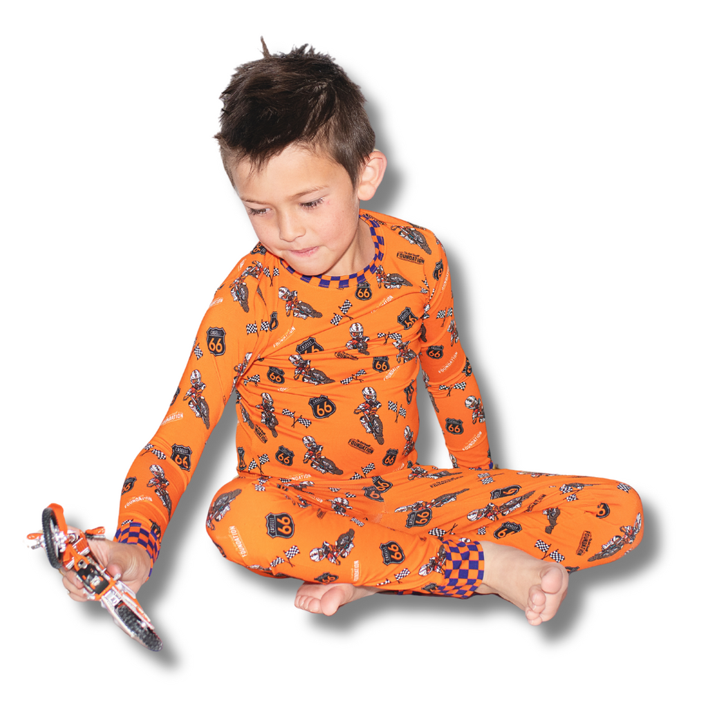 Orange pajama set on child: long-sleeve top and matching pants with racing print
