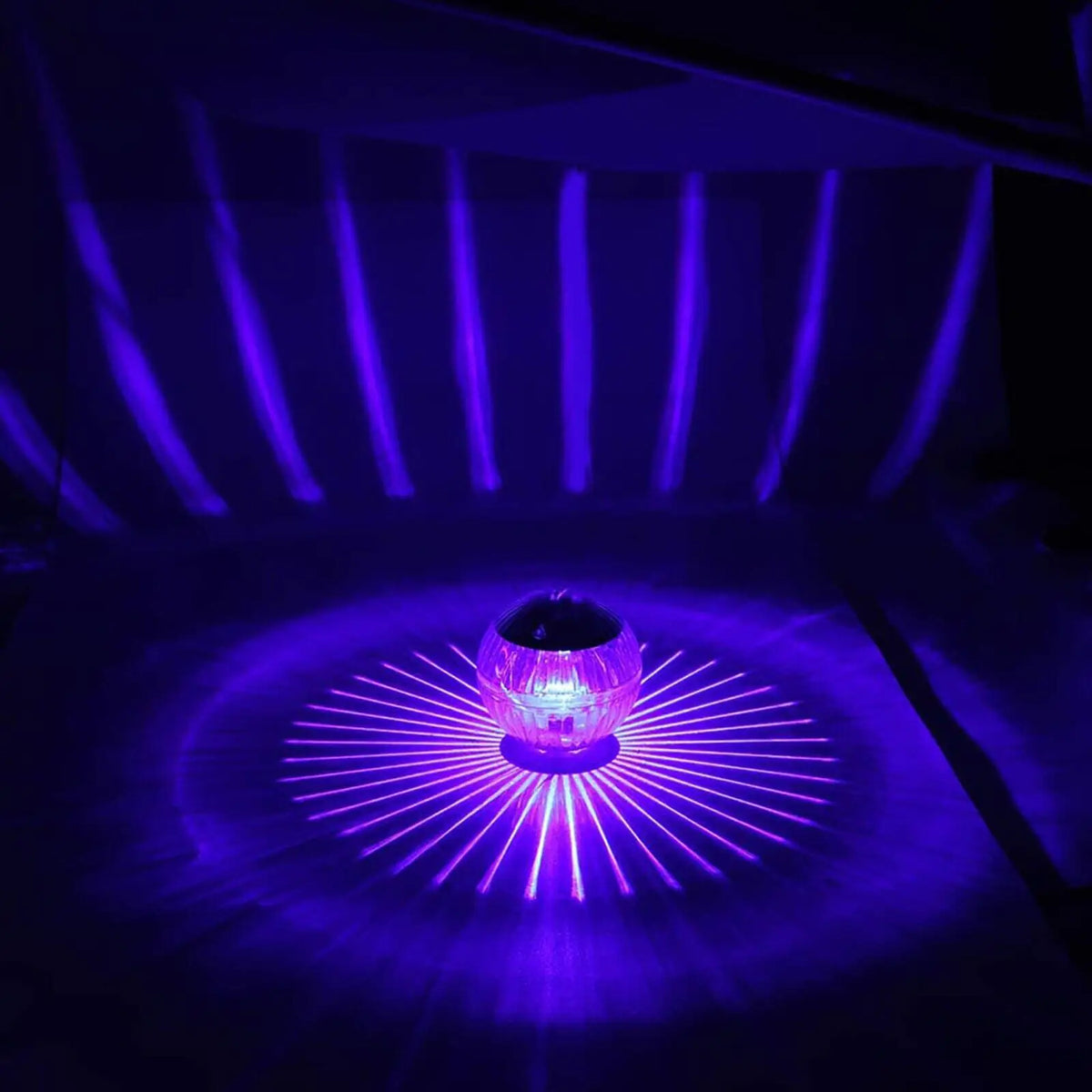 Solar LED floating dome lamp casting bright purple light starburst