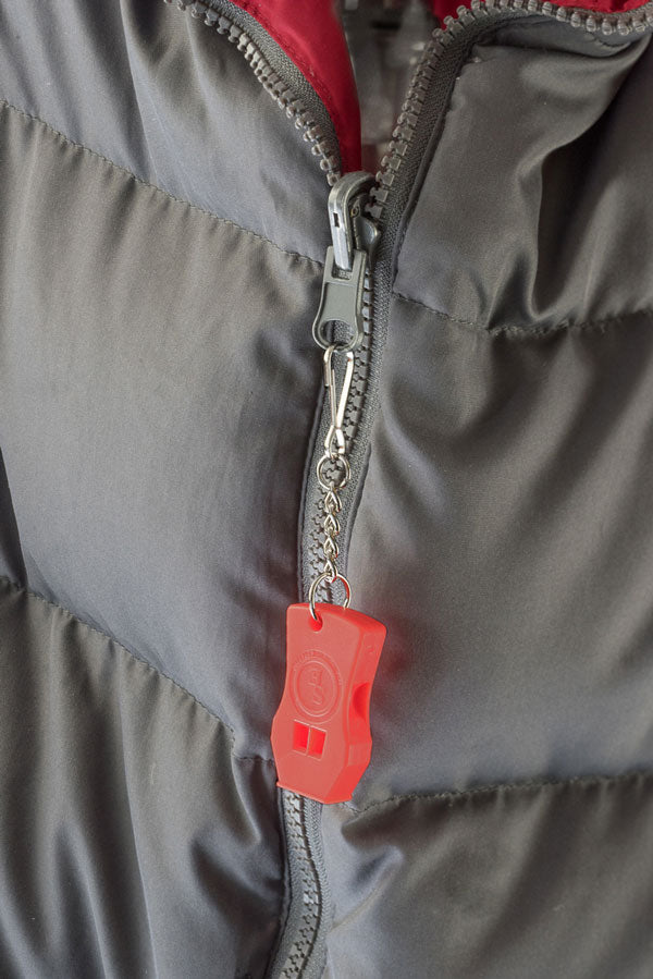 Red plastic whistle on metal chain attached to jacket zipper pull