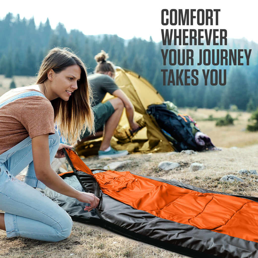 Orange and black sleeping bag laid out for camping use
