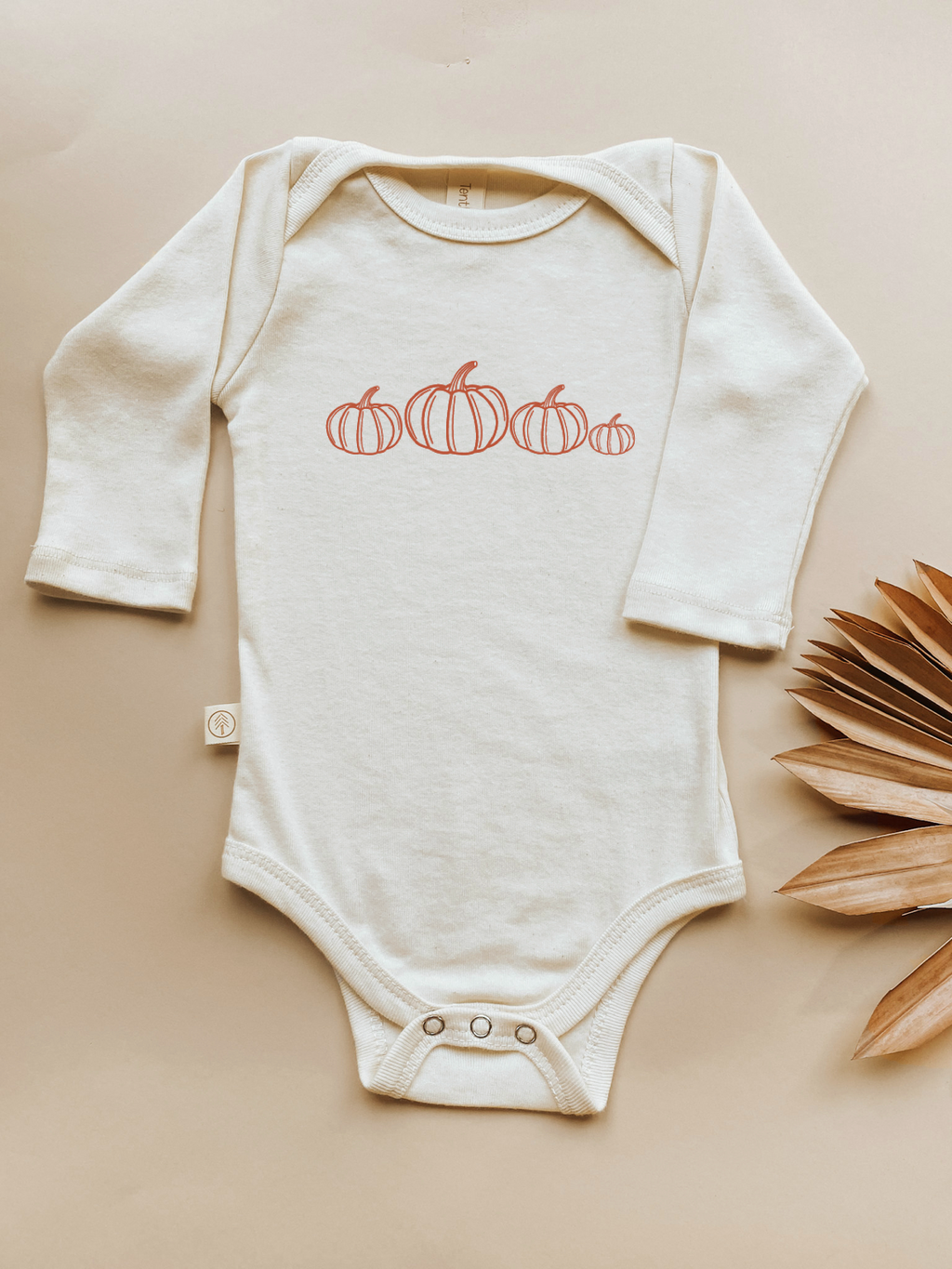 Cream long-sleeve bodysuit with orange pumpkin print and snap front placket