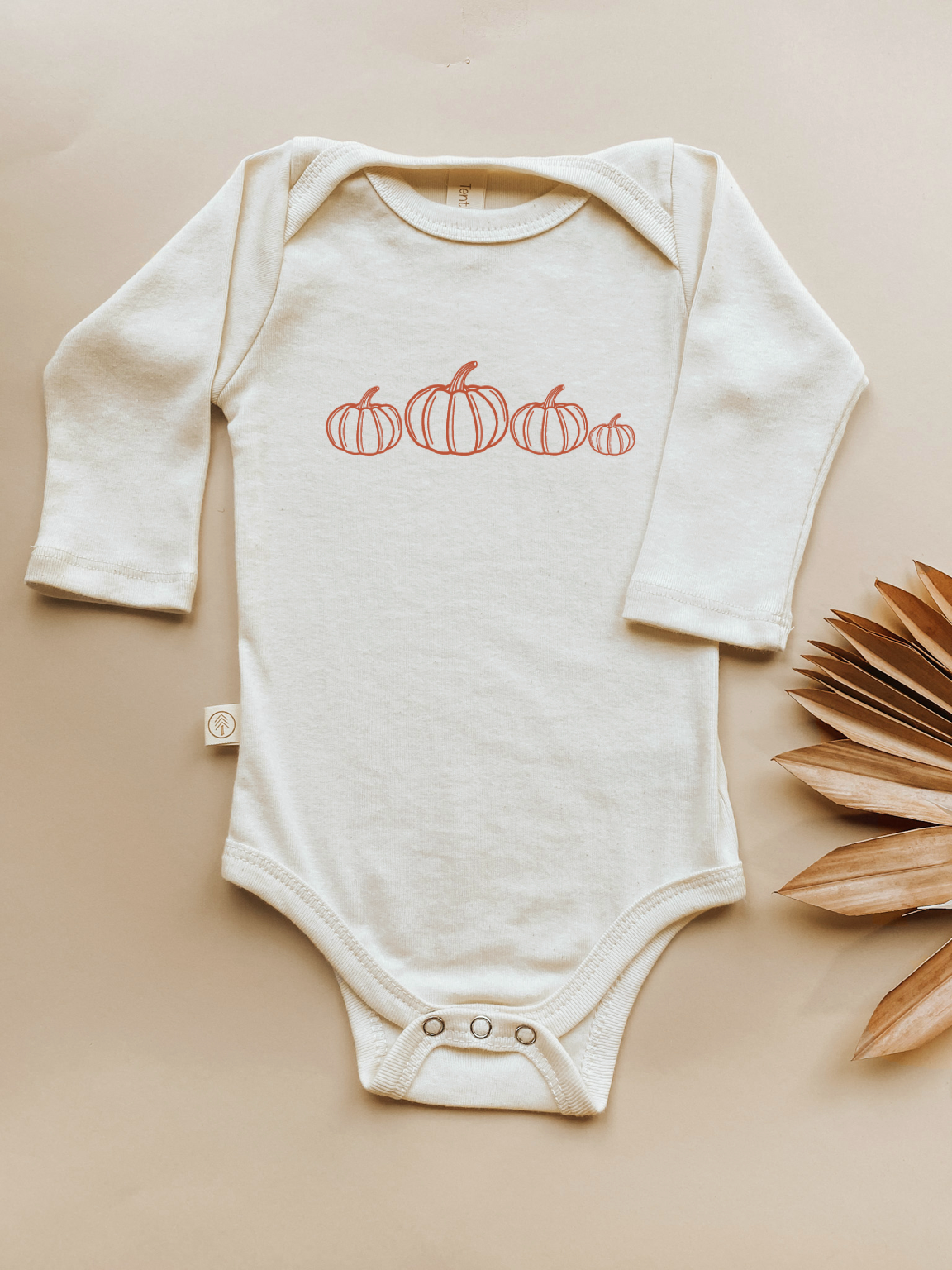 Cream long-sleeve bodysuit with orange pumpkin print and snap front placket