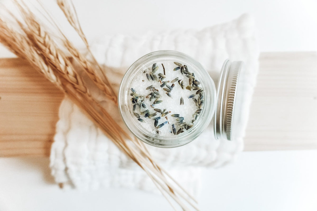 Lavender Meadows Co bowl tin with speckled dried herb mixture beside a comb