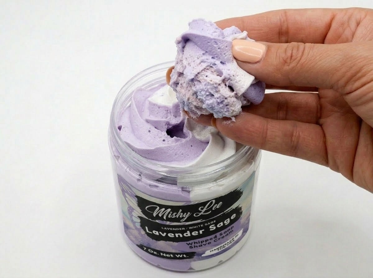 Hand holding a scoop of purple whipped soap and shave cream from a jar
