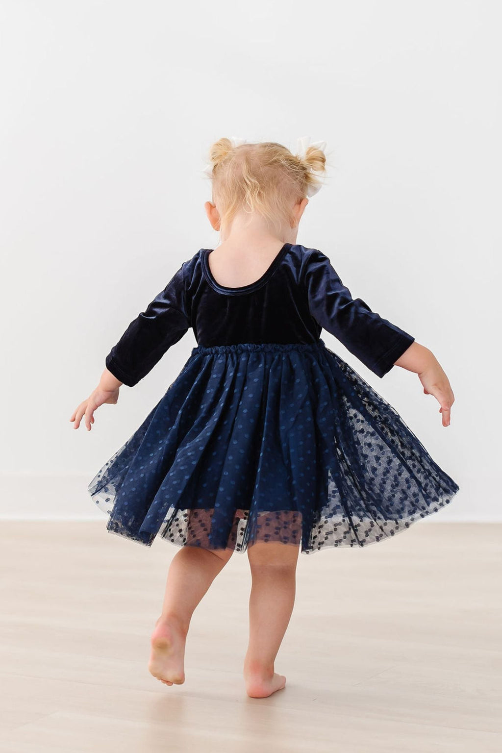 Navy velvet long-sleeve tutu dress, back view with twirled flared tulle skirt