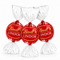 Milk chocolate truffles in red Lindt LINDOR foil, with white paper wrap pieces.