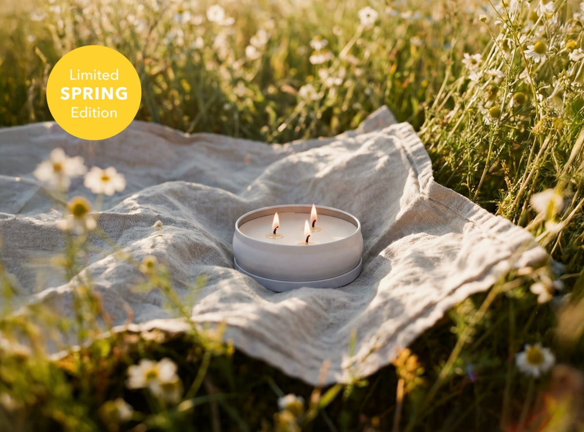 Small 3-wick candle in light-blue container on outdoor fabric cloth