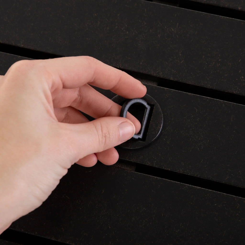Hand turning the control knob on a dark rectangular fire pit table.