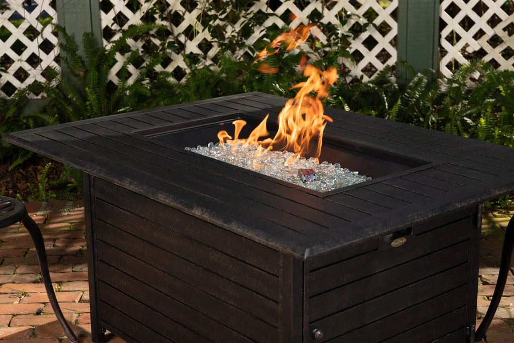 Dark rectangular gas fire pit table with visible flames over glass fire media.