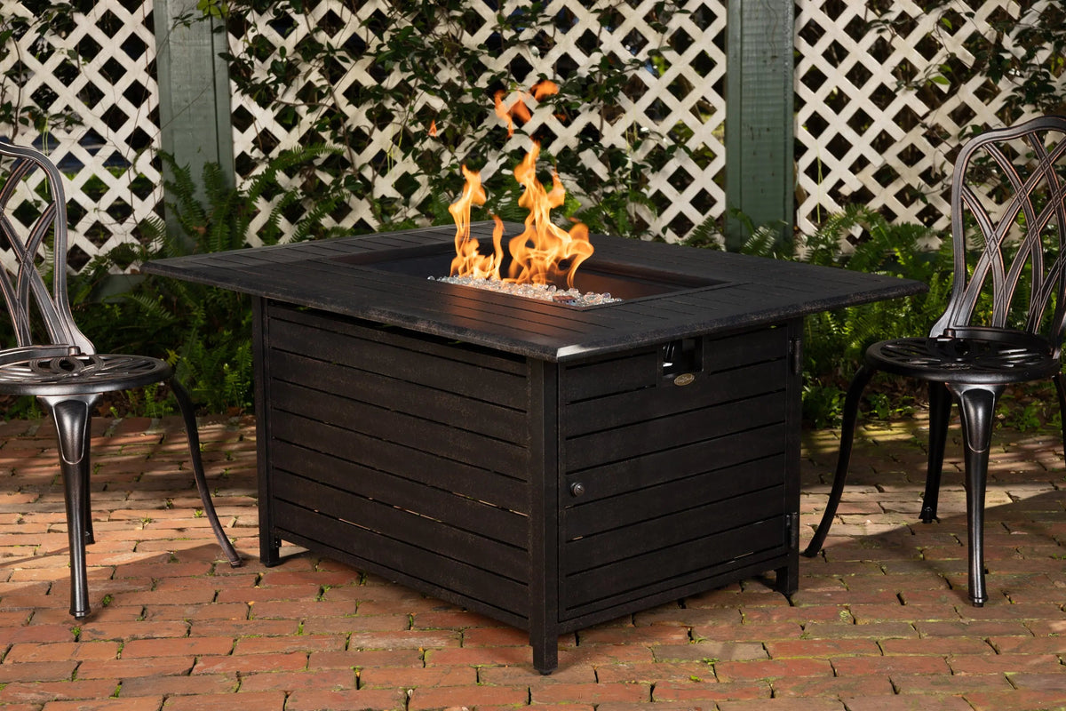 Rectangular dark gas fire pit table with active flames and glass fire media in center.