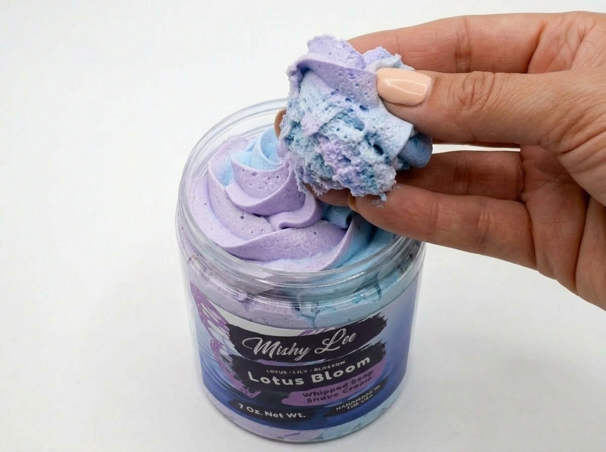 Hand scooping pastel purple and blue whipped soap from a jar