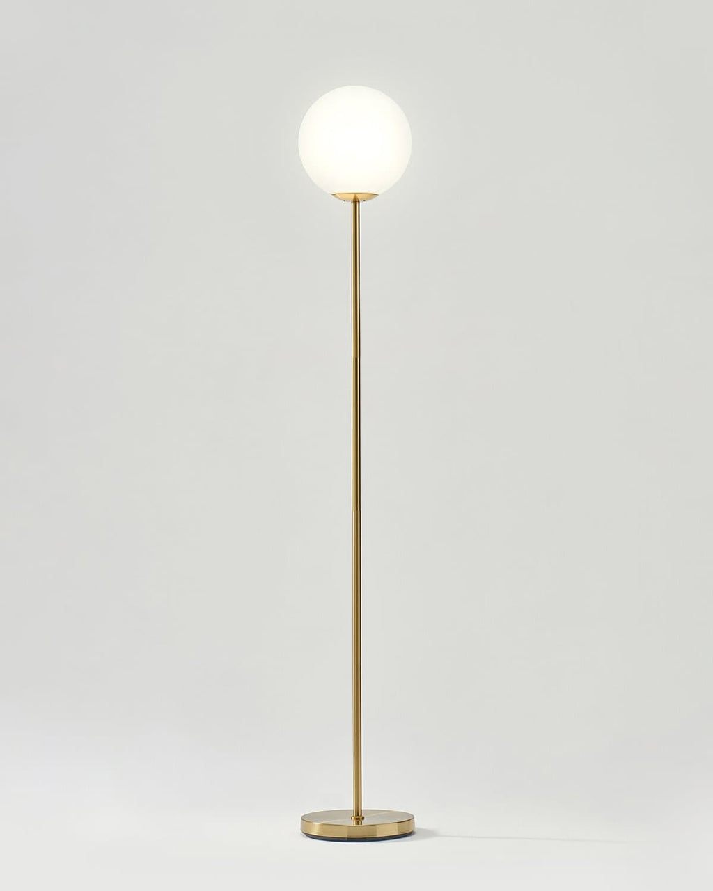 LED floor lamp with antique brass pole, frosted round globe shade, and circular base