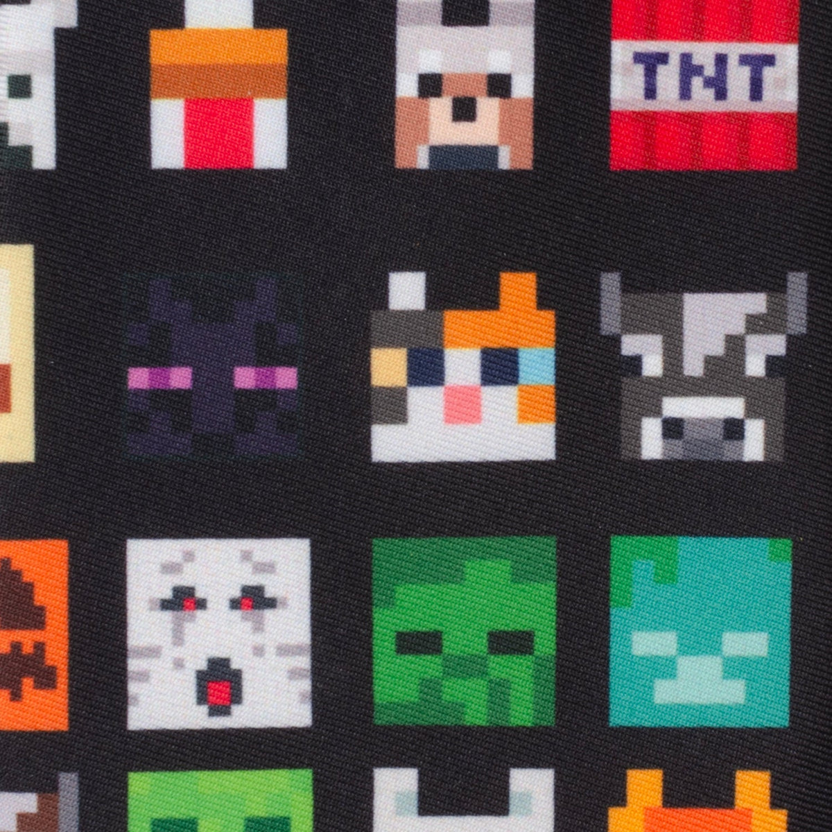 Close-up of black men's tie fabric with pixel art faces and TNT block icons