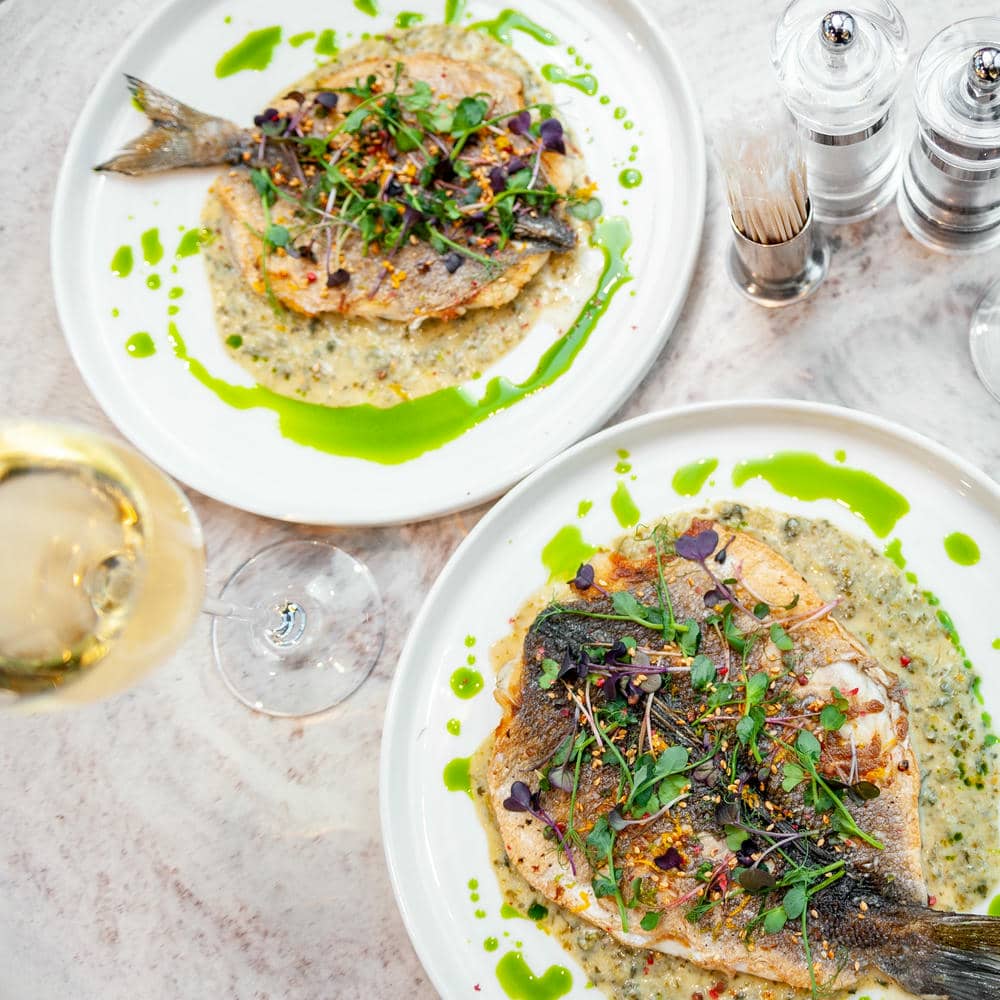 Mediterranean kitchen gift set two plated fish entrees with green herb oil.