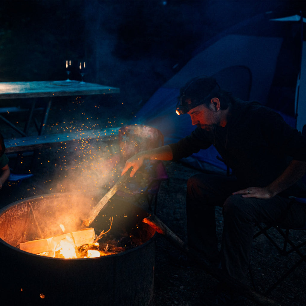Outdoor headlamp glowing while tending a firepit