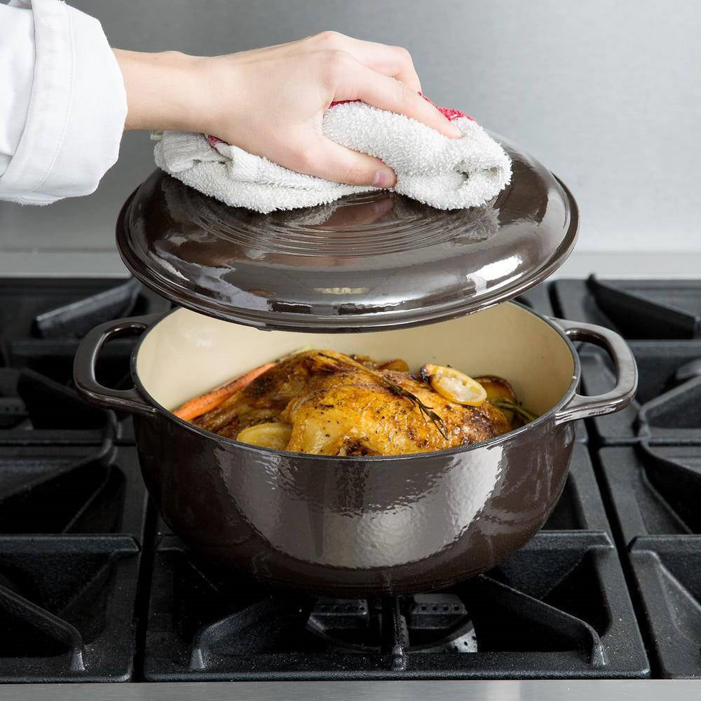 Black enamel Dutch oven with lid open, chicken inside, side handles