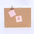 Standing cork bulletin board with gold metal clips and pins, holding pink notes