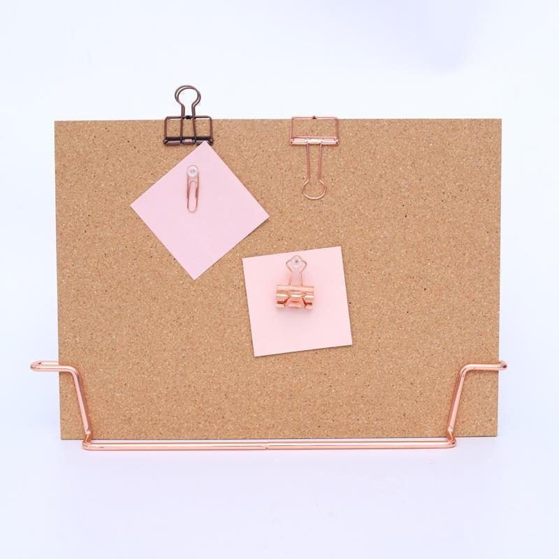 Standing cork bulletin board with rose gold metal clips and pins, holding pink notes
