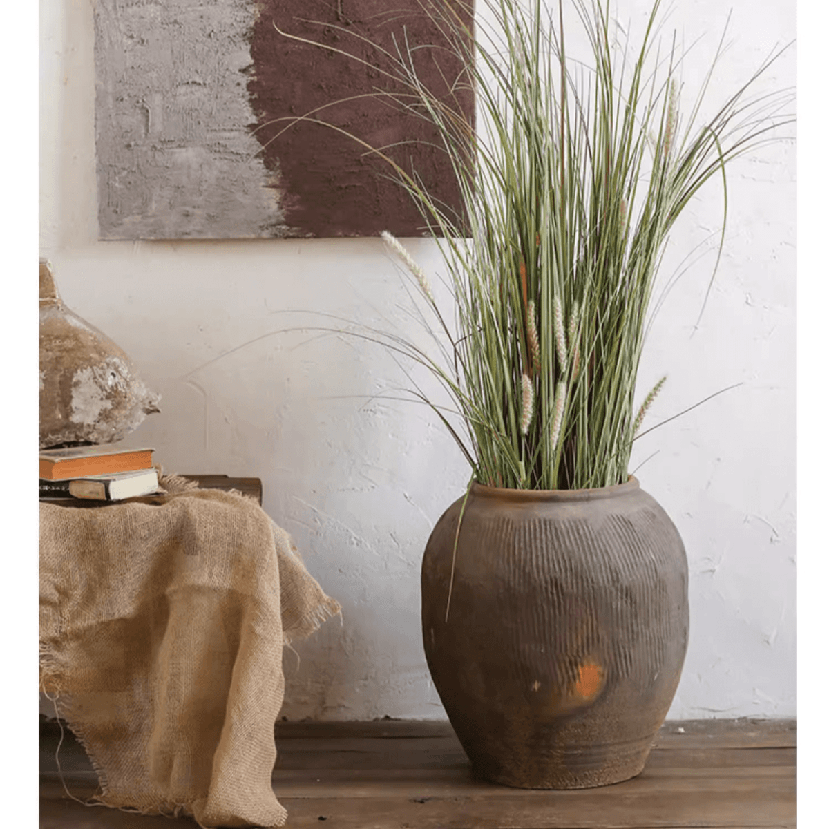 Brown ribbed earthenware vase pot with wide opening holding tall grass
