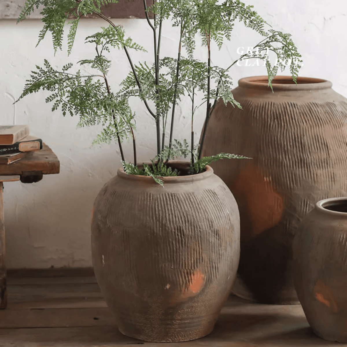 Brown ribbed earthenware round pot with wide opening and leafy plants