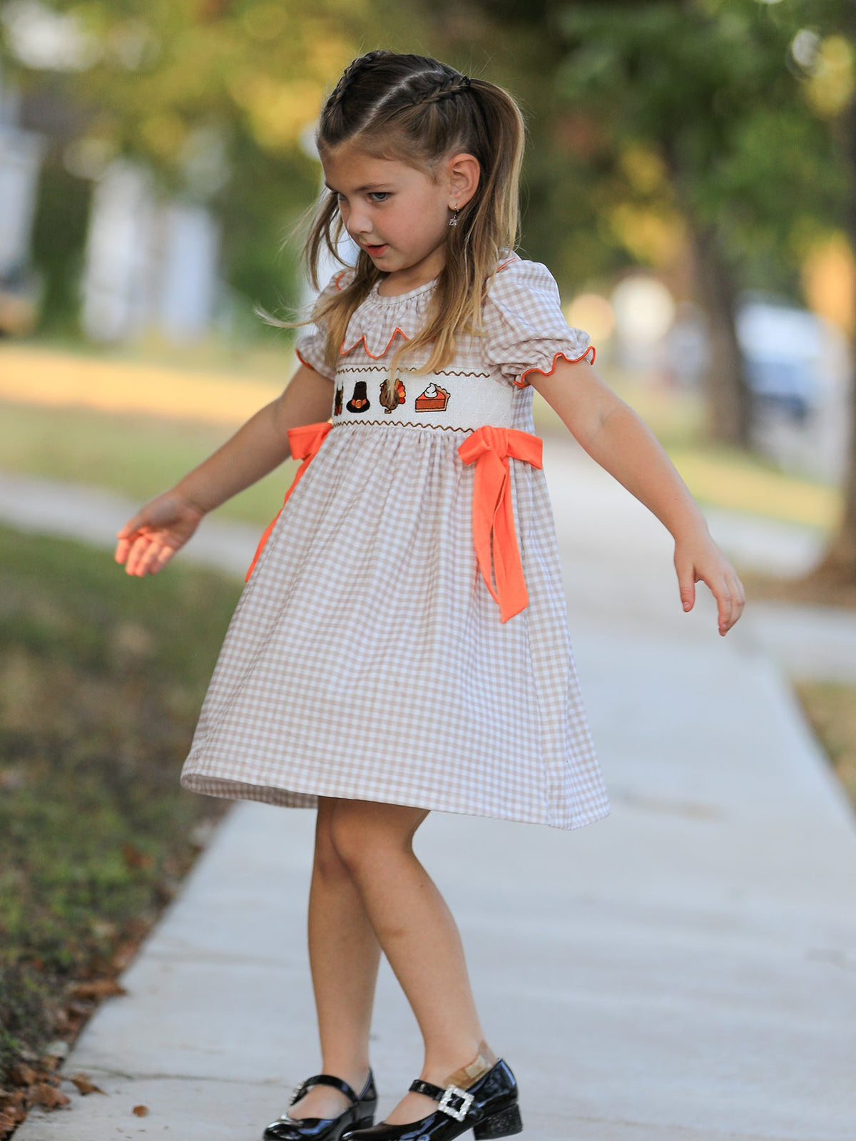 Girls gingham Thanksgiving dress viewed from side, orange ribbon bows at waist