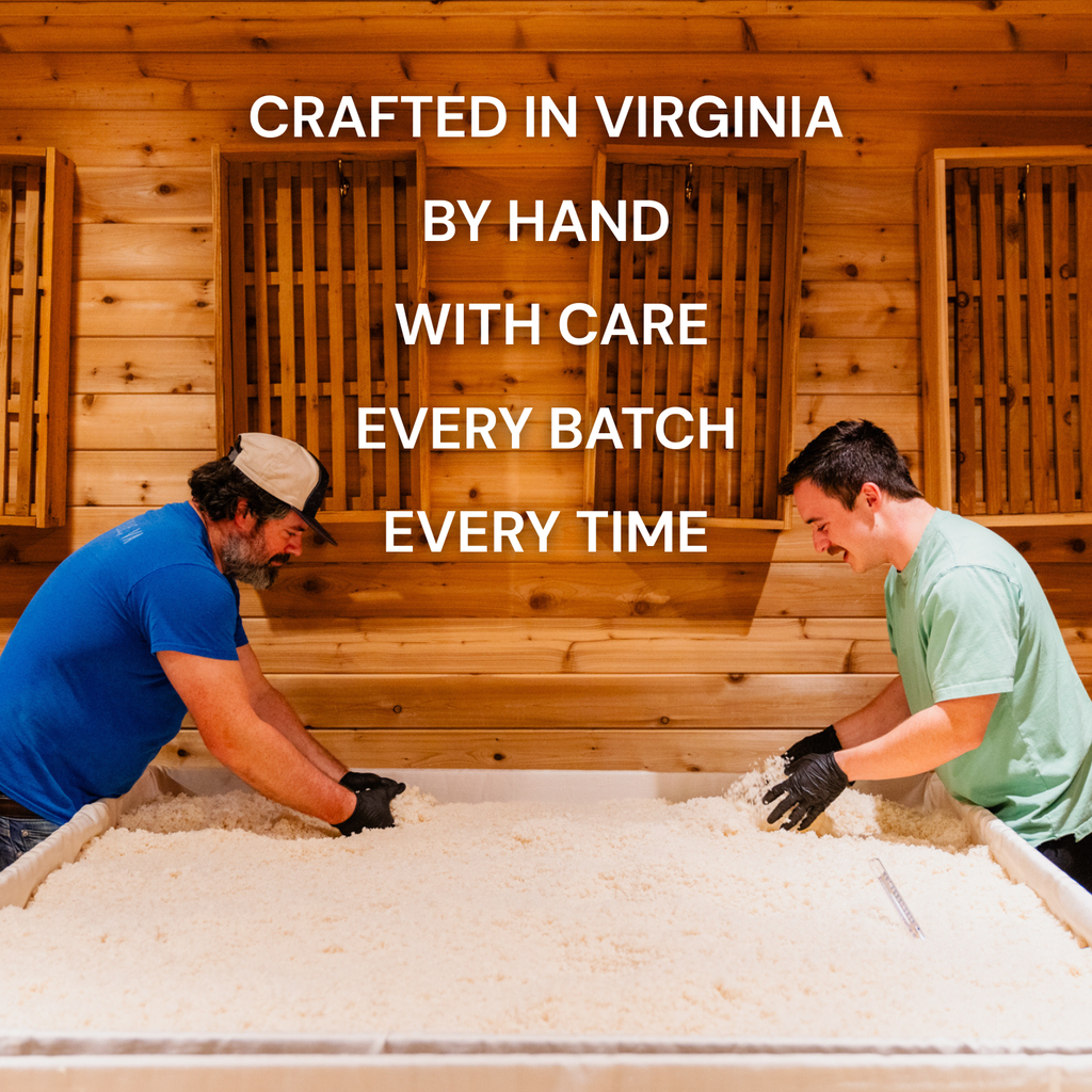 Workers spreading white rice koji on a large tray in a wooden workshop