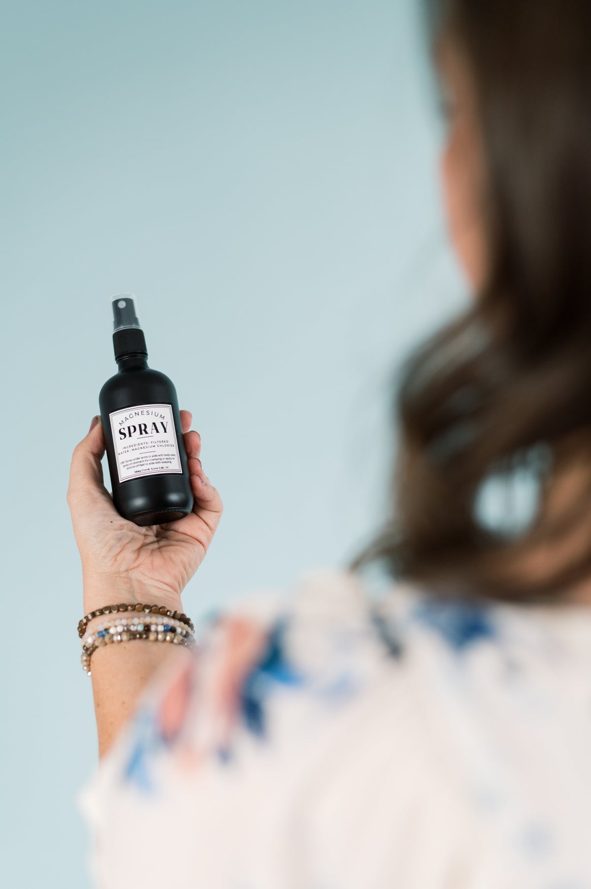 Hand holding magnesium spray bottle with mist sprayer, label facing outward