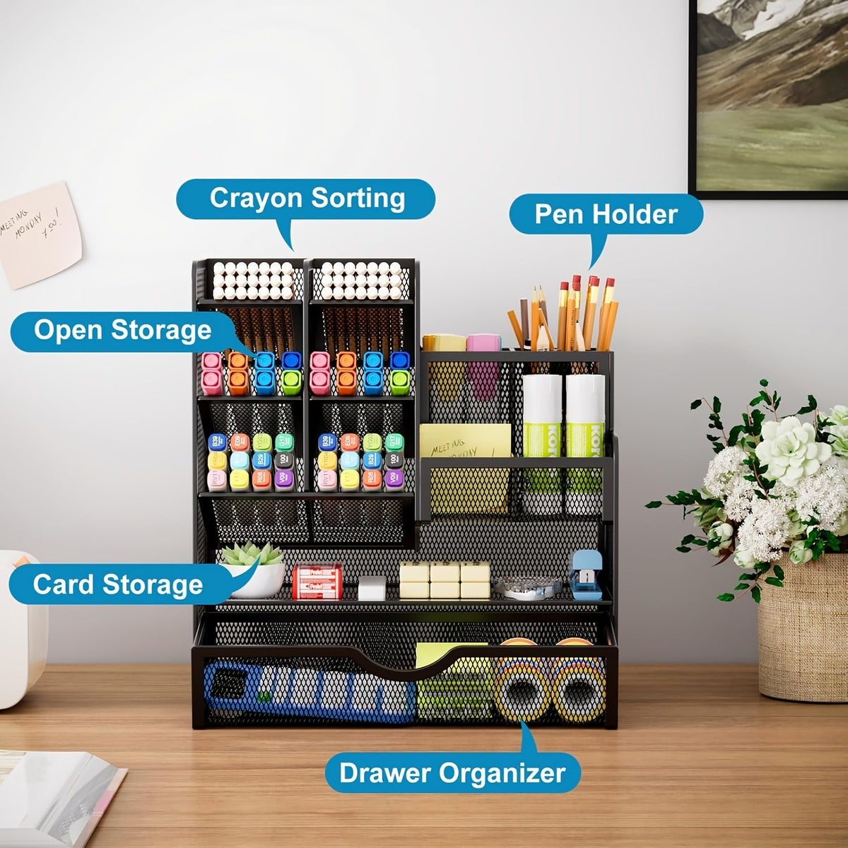Black iron mesh desk organizer with open storage trays and front drawer, holding stationery