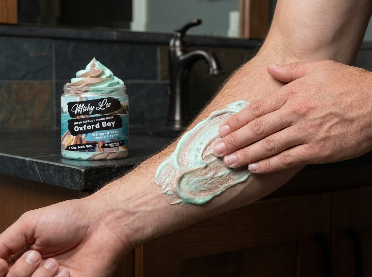 Men’s shaving cream spread on hands with teal and tan whipped lather, jar nearby